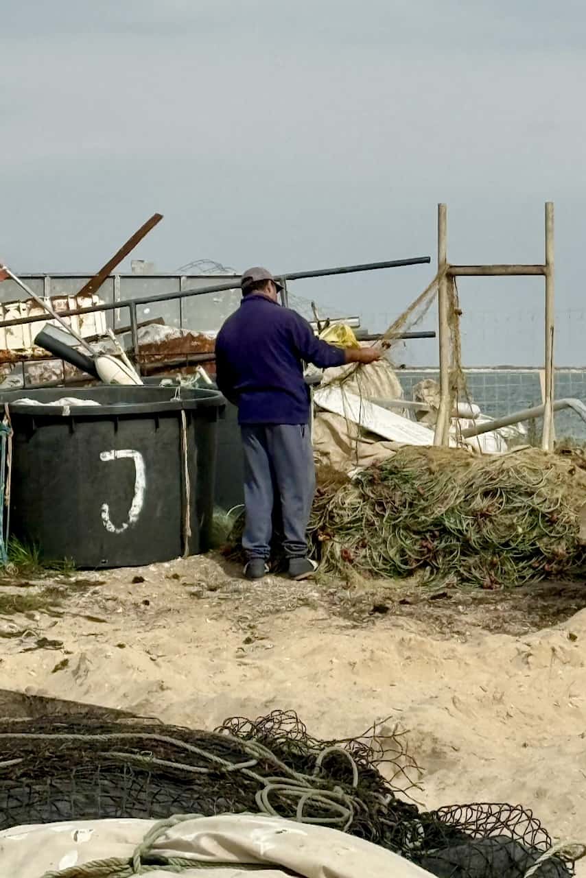 Fisherman mending his nets at Culatra