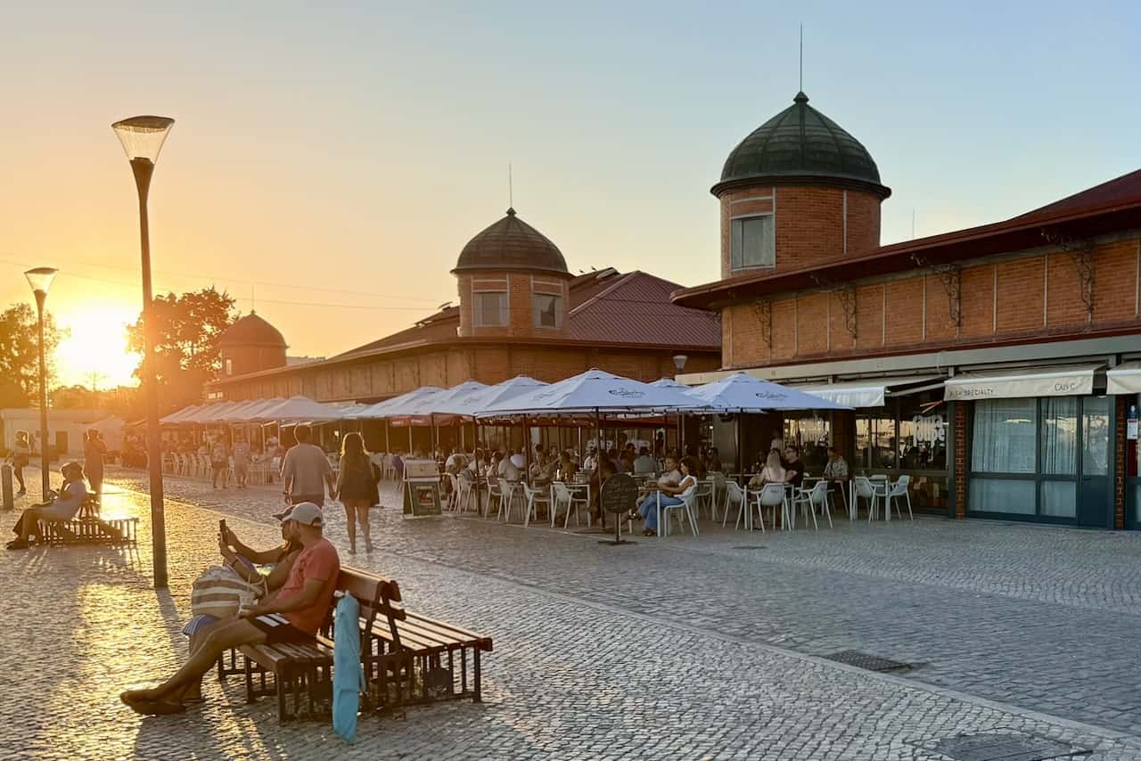 De iconische markthallen van Olhão, omringd door levendige terrassen in het warme licht van een zomerse zonsondergang.